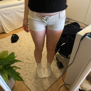 Beige shorts från Hollister - Snygga beige shorts från Hollister med låg midja och klassisk design. Perfekta för varma sommardagar. De har en knapp och dragkedja framtill samt fickor både fram och bak. Är helt nya med lapp. Är i storlek w23. Ifall ni undrar mer om måtten på shortsen skriv privat!