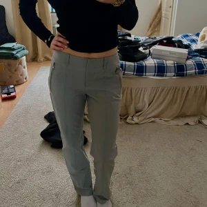 Grå byxor med dragkedjedetaljer - Snygga grå byxor med dragkedjor på sidorna. De har en låg midja och raka ben, vilket ger en stilren look. Perfekta för en chic vardagsstil. Materialet är smått prassligt men håller sig ändå mjukt och tunt. 