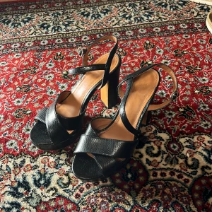 Svarta hög klackar - Snygga svarta  hög klackar och justerbara remmar. Perfekta för en elegant look. Klackarna ger extra höjd och stil.