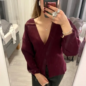 Vinröd kofta med v-ringning - Snygg vinröd cardigan med v-ringning och långa ärmar. Perfekt för en stilren look. Passar bra till både jeans och kjol.