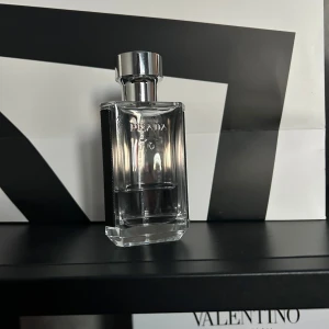 Prada parfym i genomskinlig flaska - Elegant parfym från Prada i en stilren, genomskinlig glasflaska med silverfärgad kork. Flaskan har en rektangulär form och utstrålar lyx och enkelhet. Perfekt för den som uppskattar en tidlös och sofistikerad doft.