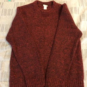 Vinröd stickad tröja från H&M - Säljer en vinröd stickad tröja från H&M. Tröjan har en klassisk rund hals och långa ärmar, perfekt för kyligare dagar. Den är mjuk och bekväm, idealisk för både vardag och avslappnade tillfällen.