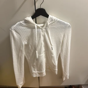 Vit ribbad hoodie från Dazy - Säljer en stilren vit ribbad hoodie från Dazy. Den har en dragkedja framtill och en praktisk huva med snörning. Perfekt för en avslappnad look. Använd 2 gånger!!
