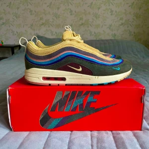 Nike Air Max 1/97 Sean Wotherspoon - Unika Nike Air Max 1/97 Sean Wotherspoon sneakers med en färgglad design i gult, blått och brunt. Skorna har en vågig mönsterdesign och är tillverkade i en kombination av material för en retro look. Perfekta för sneakerentusiaster! 