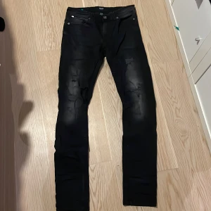 Svarta jeansbyxor från Smog - Snygga svarta jeansbyxor från Smog i storlek 29/32. Byxorna har en slim passform och är tillverkade i ett stretchigt material för extra komfort. Perfekta för en stilren look.