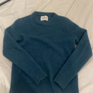 Blå ulltröja från These Glory Days - Säljer en snygg blå tröja från These Glory Days, tillverkad i 100% lammull. Tröjan har en klassisk rund hals och långa ärmar med ribbade muddar. Perfekt för kyliga dagar! 