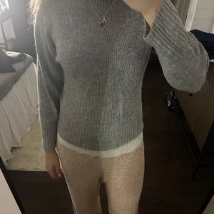 Grå stickad tröja - Mysig grå stickad tröja med långärmad design. Perfekt för kyligare dagar med sin ribbade struktur som ger en stilren look.