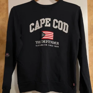 Mörkblå tröja från The Defender - Säljer en mörkblå tröja från The Defender med tryck framtill. Storlek S.