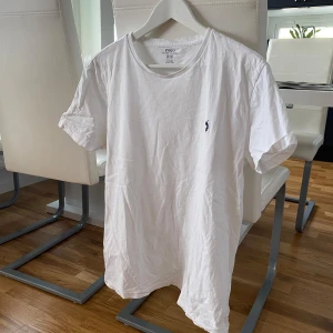 Vit t-shirt från Polo Ralph Lauren - Säljer en klassisk vit t-shirt från Polo Ralph Lauren i storlek M. Den är i mycket bra skick och har en liten broderad logga på bröstet. Perfekt för en stilren och avslappnad look. Passar till alla tillfällen!