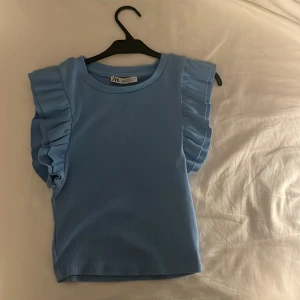 Blå ribbad topp från Zara - Säljer en superfin blå ribbad topp med volangärmar från Zara i storlek S. Lite små nopprig men inget man tänker på! Bara använd ett fåtal gånger💕💕
