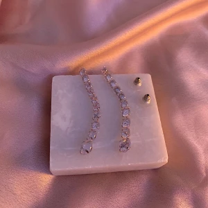 Glittriga örhängen i silver - Säljer ett par superfina glittriga örhängen i silver. De är långa och eleganta, perfekta för fest eller nyår. Örhängena har en rad av gnistrande stenar som fångar ljuset på ett magiskt sätt. Passar perfekt till en glamorös outfit! ✨