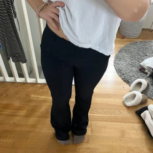 Mörkblåa kostymbyxor  - Säljer ett par mörkblåa kostymbyxor i bootcut-stil. De är lågmidjade och har en snygg passform som passar perfekt till både vardag och fest. Materialet är mjukt och stretchigt, vilket gör dem superbekväma att ha på sig hela dagen.