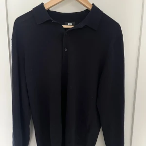 Blå stickad tröja - Säljer en stilren blå tröja från Uniqlo. Den har en klassisk krage och knäppning framtill. Perfekt för både vardag och lite finare tillfällen. Passar bra till höst och vinter.