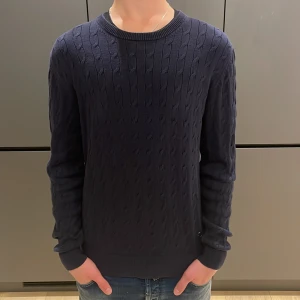 J.lindeberg tröja - Riktigt schysst J.Lindeberg kabelstickad tröja med den unika detaljen av J.L märket. Tröjan är varm och go inför hösten och vintern. Storlek M. Priset är ej hugget i sten.