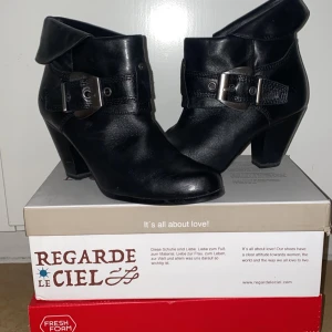 Svarta boots från Tamaris - Säljer ett par snygga svarta boots från Tamaris. De är i skinn och har en cool spänndetalj på sidan. Perfekta för höst och vinter med en stabil klack som ger lite extra höjd. De är i nyskick och redo att användas till både vardag och fest!