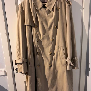 Vintage trenchcoat - Säljer denna otroligt fina vintage trenchcoaten inköpt secondhand i Paris. Trenchcoaten är tillverkad i Italien med fina detaljer och löstagbart foder på insidan vilket gör att den både passar vinter och höstbruk. Finns två fläckar se bilder