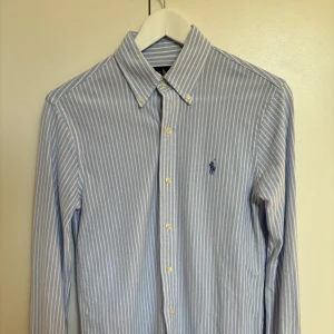 Randig Ralph Lauren Skjorta - Tja! Säljer denna sjukt snygga ljusblåa skjortan från Ralph Lauren. Den är i perfekt skick och har knappats använts, säljer då den är för liten för mig. Nypris ligger på ungefär 1 300kr men säljer min för endast 499kr! Hör av dig vid prisfunderingar!