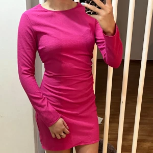 Rosa klänning med lång ärm - Säljer en superfin rosa klänning med lång ärm. Den är tight och har en kort längd, perfekt för festliga tillfällen. En riktig färgklick i garderoben!