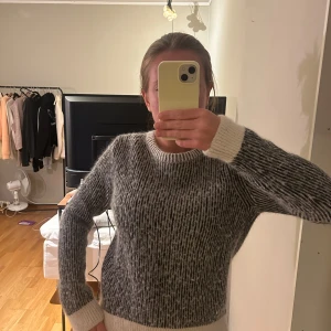 Grå och vit stickad tröja - Säljer en supermysig grå och vit stickad tröja. Den har en klassisk rund hals och långa ärmar, perfekt för kyliga dagar. Tröjan är i bra skick. Den är ifrån & other stories.