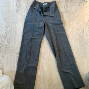 Grå kostymbyxa  - Grå kostymbyxa från NAKD. Aldrig använda då de är för långa för mig. Strl 32. Byxorna har en slits på baksidan längst ned på benen. 