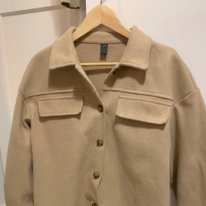 Beige kappa - Kappan är jättevarm och värmer dig mot det kalla vädret.  Den har stora fickor i framsidan för dina föremål.  Plagget är bara använd några gånger men är fortfarande i jättebra kondition.