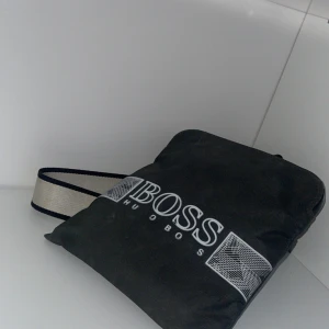 Hugo boss   - Väldigt fin väska dessutom finns den inte på marknaden längre. finns täken på användning men annars inga skador