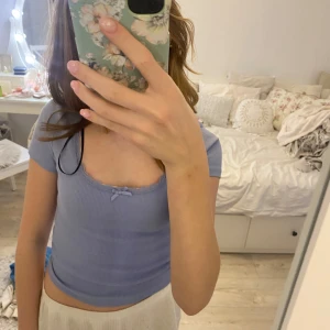 Ljusblå ribbad topp från H&M Divided - Säljer en söt ljusblå ribbad topp från H&M Divided med spets och en rosett. PRIS GÅR ATT DISKUTERA! Fint skick, använd runt 2 ggr.💕