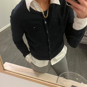 Tröja från Tommy Hilfiger - Tröja från Tommy Hilfiger med knappar framtill. Perfekt för lager-på-lager-stil med en vit skjorta under. 