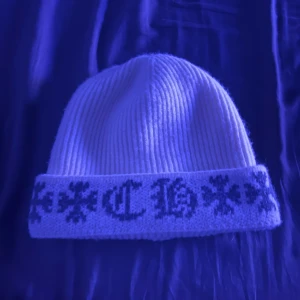 Vit ribbad mössa med broderad text - Snygg vit ribbad mössa med broderad text i svart. Perfekt för att hålla värmen med stil under kyliga dagar. Den har en klassisk passform och är lätt att matcha med olika outfits.