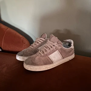 Bruna sneakers från Valentino - Snygga bruna sneakers från Valentino med en stilren design. Skorna har snörning och är tillverkade i mocka med en vit sula. Perfekta för en avslappnad stil behövs bara en tvätt .