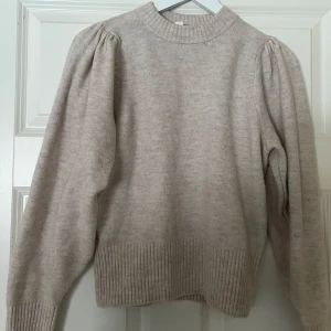 Beige stickad tröja från H&M - Säljer en stilren beige stickad tröja från H&M. Tröjan har långa ärmar med puffiga axlar och ribbade muddar.💖💗✨