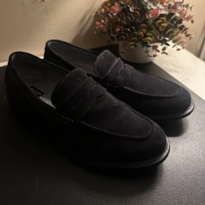Marinblå loafers från Sand - Snygga marinblåa loafers i mocka från Sand. Perfekta för en stilren look med en klassisk design och bekväm passform. De har en elegant och tidlös stil som passar till många olika tillfällen, perfekta till sommaren.