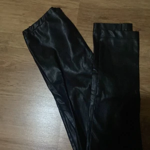 Svarta skinnleggings - Snygga svarta leggings i skinnimitation med elastisk midja. 