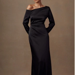 Elegant svart maxi klänning  - Elegant svart långklänning med en offshoulder-design och långa ärmar. Den är helt ny och har alla lappar kvar. Klänningen har ett fint silkigt material som är perfekt för speciella tillfällen som bal eller bröllop! Pris kan diskuteras:)