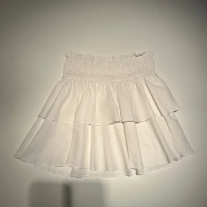 Vit volangkjol från Shein! - Säljer en söt vit volangkjol från Shein i storlek XS. Kjolen har en elastisk midja och flera lager volanger. Säljer då den inte kommer till användning och säljer billigt pga de små defekterna och märket. Defekterna syns inte utåt❤️ Pris kan diskuteras 