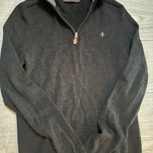 Svart merinoulltröja från Morris - Säljer en stilren svart tröja från Morris i 100% merinoull. Tröjan har en praktisk dragkedja vid halsen och en liten broderad detalj på bröstet. Perfekt för kyligare dagar. Storlek M men passar S. Nyskick, knappt använd.