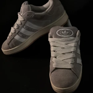 Grå Adidas sneakers - Snygga grå Adidas sneakers med klassiska tre ränder i vitt på sidan. Skorna har en bekväm passform och är perfekta för vardagsbruk. Mycket bra skick!