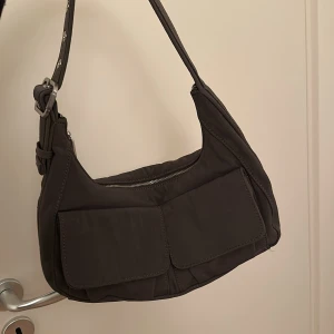 Zara väska - Snygg mörkgrå axelväska med justerbar rem och praktiska fickor framtill. Man får plats med väldigt mycket även fast den är väldigt bra i storleken. Den är använd fåtal gånger eftersom den passar mig inte i stil just nu😊