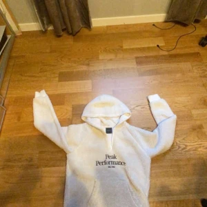 Vit hoodie från Peak Performance - Säljer en vit hoodie från Peak Performance. Den är mjuk och bekväm med en klassisk design och en stor ficka framtill. Perfekt för kyliga dagar. Hör av dig vid intresse!