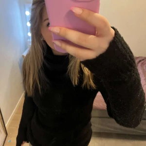 Svart polotröja - Säljer en svart polotröja med lång ärm. Tröjan har en mysig och varm design, perfekt för kyligare dagar. Den har en ribbad polokrage som ger extra komfort och stil.