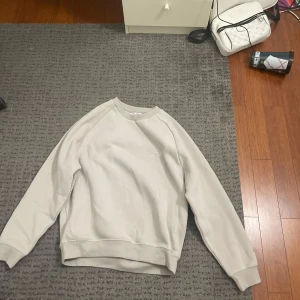 Beige sweatshirt från Saint - Säljer en stilren beige sweatshirt från Saint med broderad text på bröstet och ärmen. Tröjan har långa ärmar och en bekväm passform. Perfekt för en avslappnad look. Tröjan är helt oanvänd då den inte passa mig. Den är i Storlek XL men passar för en som har storlek M. Byxor finns även till om man skulle vilja ha de också. Köpte den för 1200 så skulle gärna vilja ha något i den stilen då den är helt oanvänd