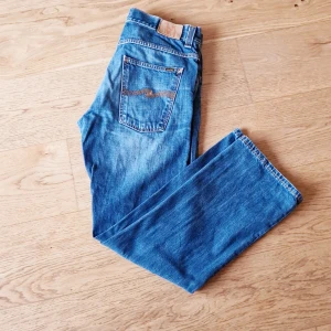  Nudie Jeans blåa - Regular fit blå jeans från Nudie. Supersnygg ljusare tvätt, inga slitningar eller hål. Sparsamt använda. Storlek: W34/L32