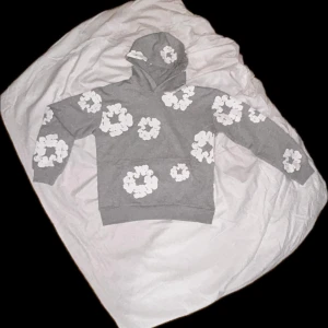 Denim Tears - (PRIS KAN DISKUTERAS) Säljer en grå hoodie från Denim Tears med ett unikt vitt blommönster. Hoodien har en klassisk passform med långa ärmar och en bekväm huva. Perfekt för en avslappnad stil. Den är riktig!. Väldigt hög kvalite, bara använt en gång på test men annars helt sprillans. 
