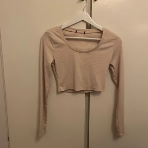 Beige croppad långärmad topp - Snygg beige croppad topp med långa ärmar. Perfekt för en stilren look. Passar bra till både jeans och kjol.