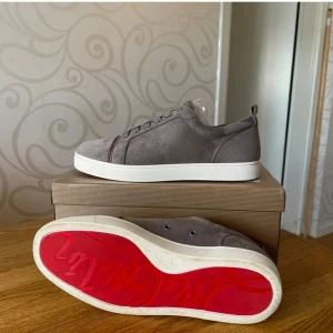 Grå sneakers med röd sula Louboutin  - Snygga grå sneakers från Christian Louboutin med den ikoniska röda sulan. Skorna har snörning och är tillverkade i mocka med en stilren design. Perfekta för en trendig look.fräsch sula som är unikt med en röd undersida 👇🥂🍾🦸‍♂️✅😉