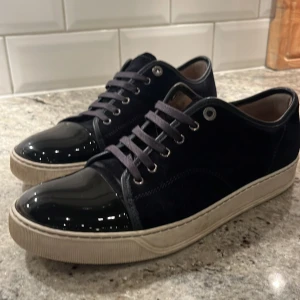 Marinblåa Lanvins - Snygga marinblåa sneakers från Lanvin med glansig tå och snörning. Skorna har en stilren design med en vit sula som ger en modern touch. Mochan är nästan helt ny inte särskilt använda. Har box och andra snören.