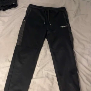 Svarta mjukisbyxor från McKenzie - Säljer ett par svarta mjukisbyxor från McKenzie med snörning i midjan och dragkedjor på fickorna. Perfekta för en avslappnad stil.