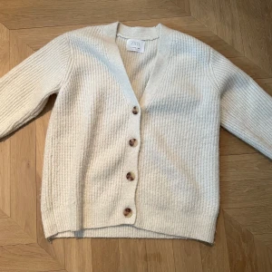 Vit kofta/cardigan från Zara - Säljer en stilren vit kofta från Zara med knappar framtill. Koftan har en ribbad struktur och långa ärmar, perfekt för kyligare dagar. Storlek 11-12 men är stor i storlek och passar på nästan alla. Väldigt bra skick och bara använd 2-4 gånger