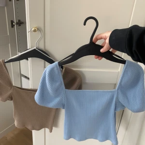 Blå och brun ribbad topp från H&M - Säljer två  ribbade toppar från H&M med korta puffärmar. En i blå och en i brun. Topparna är i storlek XS och har en bekväm passform. Båda för 10 kr. Har använt några gånger. 