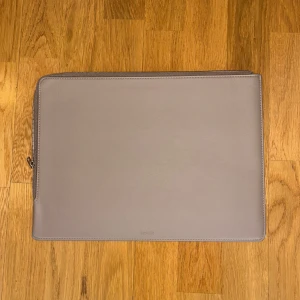 Brun datorväska från Holdit, 13 tum - Snygg och stilren grå datorväska från Holdit. Tillverkad i syntetmaterial med dragkedja längs kanten. Perfekt för att skydda din laptop med en mjuk insida.